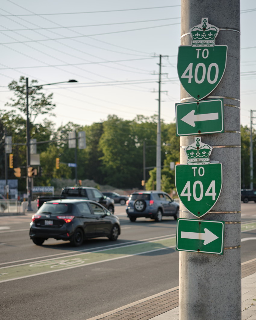 Concrete pole with stacked green signs 'TO 400' (left arrow) and 'TO 404' (right arrow); cars at intersection.